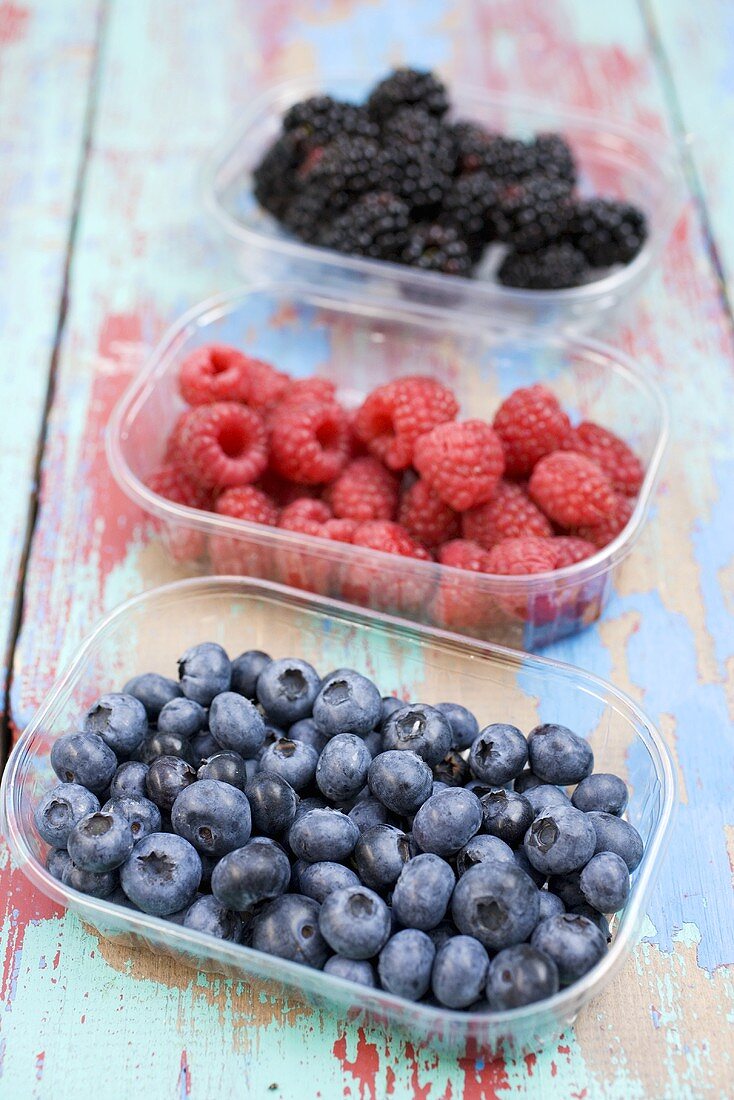 Heidelbeeren, Himbeeren und Brombeeren in Plastikschälchen