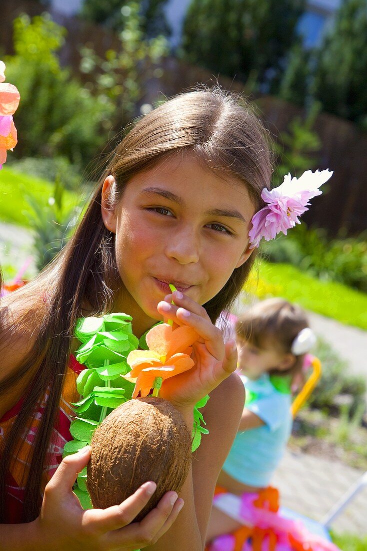 Girl drinking coconut milk out of coconut at children's party