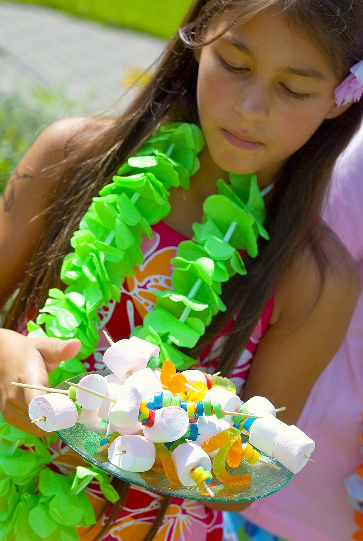 Mädchen hält Tablett mit Marshmallow-Spiesschen auf Party