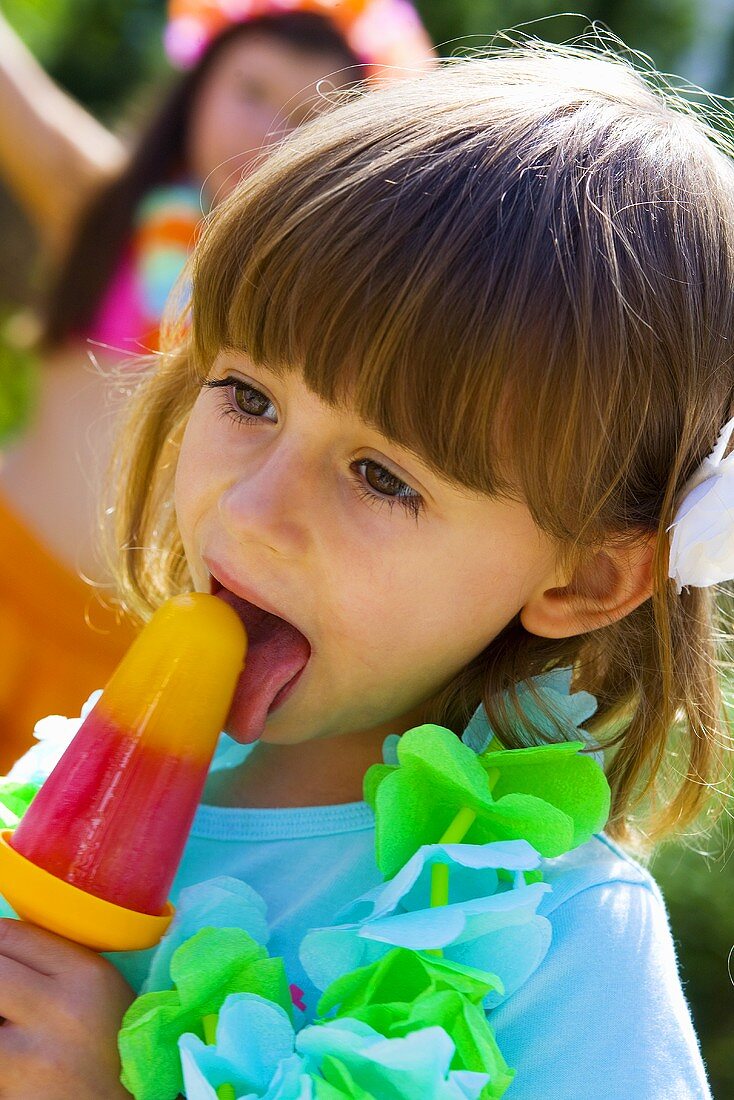 Little girl licking an ice lolly at a children's party