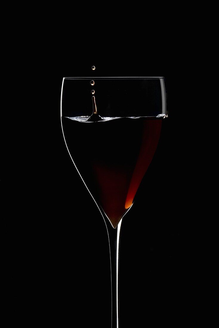 Rotwein tropft in ein Weinglas