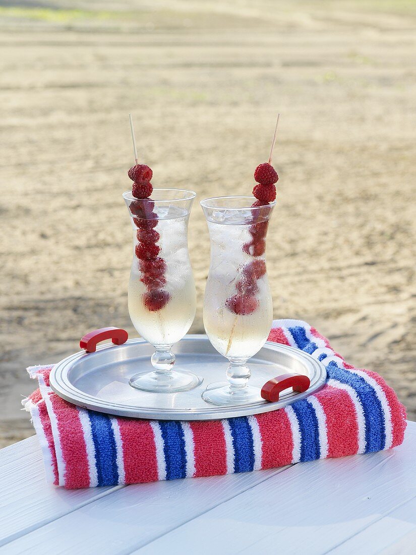 Pink Diamond cocktail with raspberry skewers on the beach