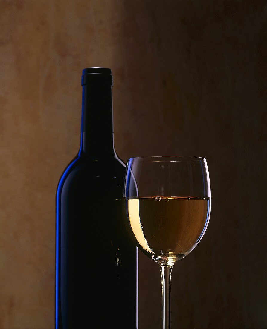 A glass of white wine and a wine bottle