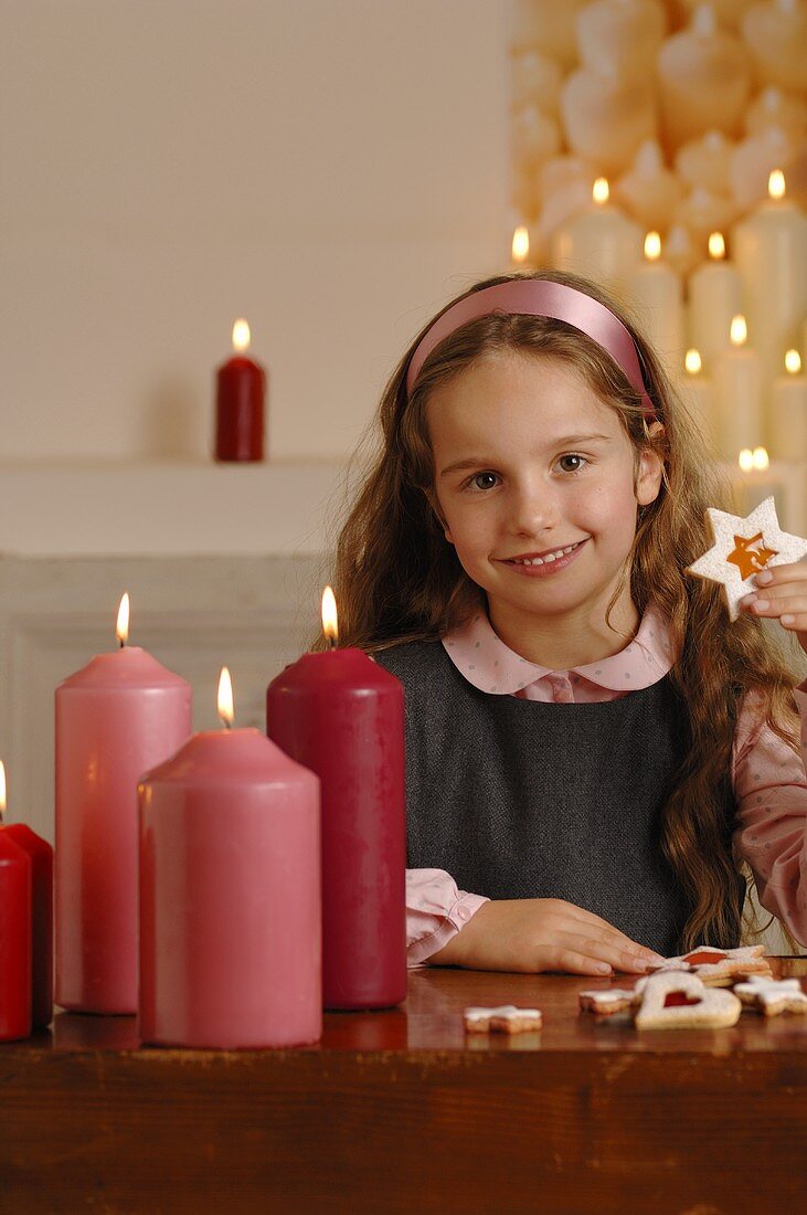 Mädchen mit Weihnachtsplätzchen und Kerzen