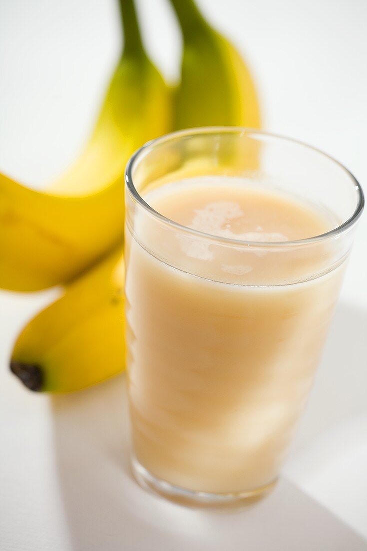 Glass of banana juice, two bananas behind