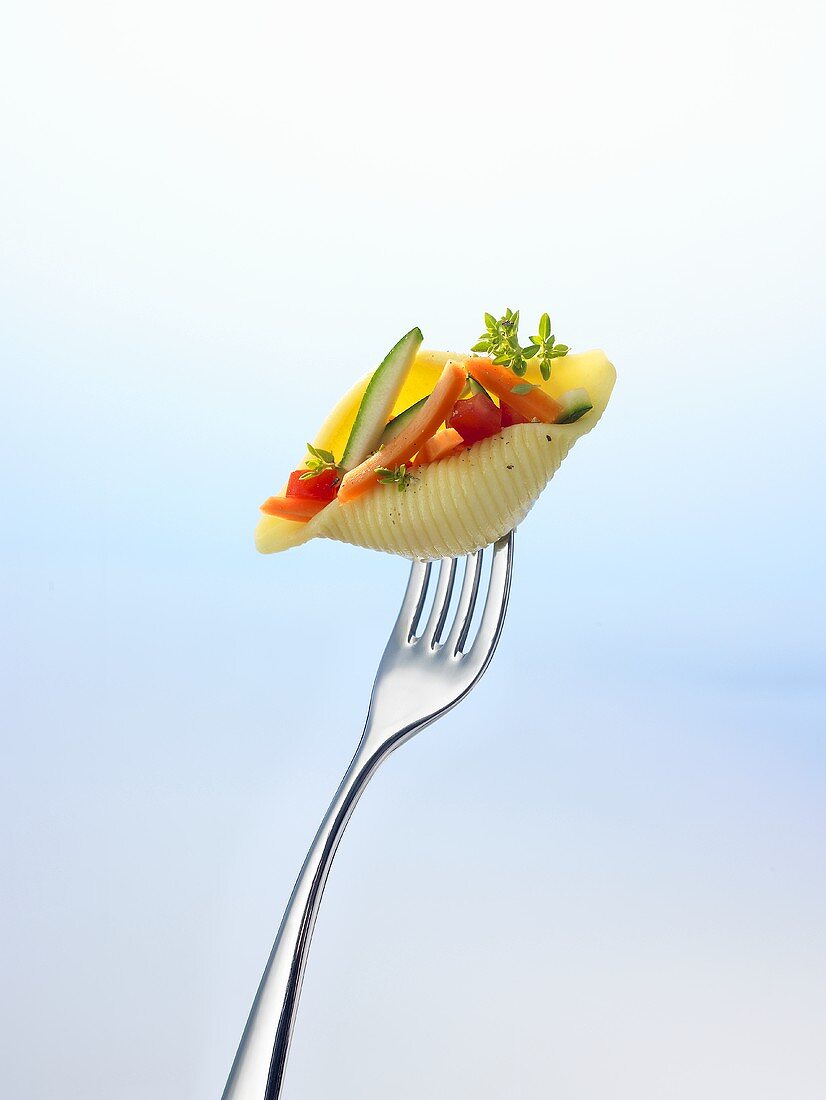 Pasta shell filled with vegetables on a fork