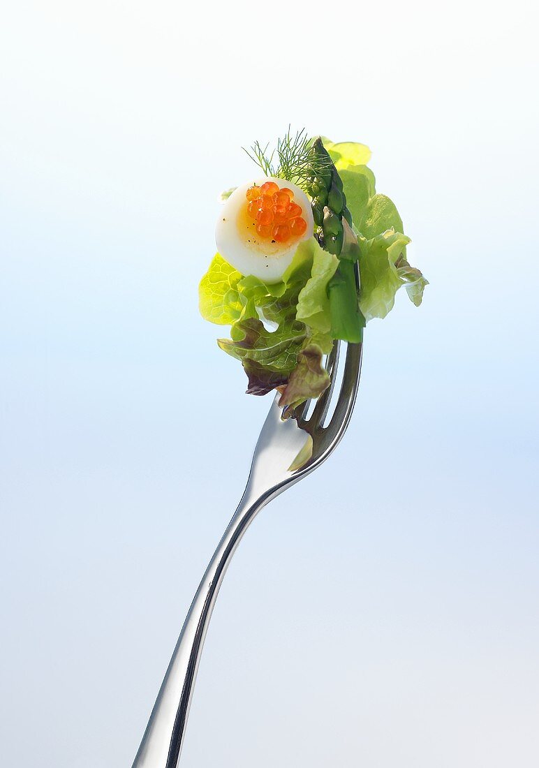 Lettuce, asparagus, quail's egg and red caviar on a fork