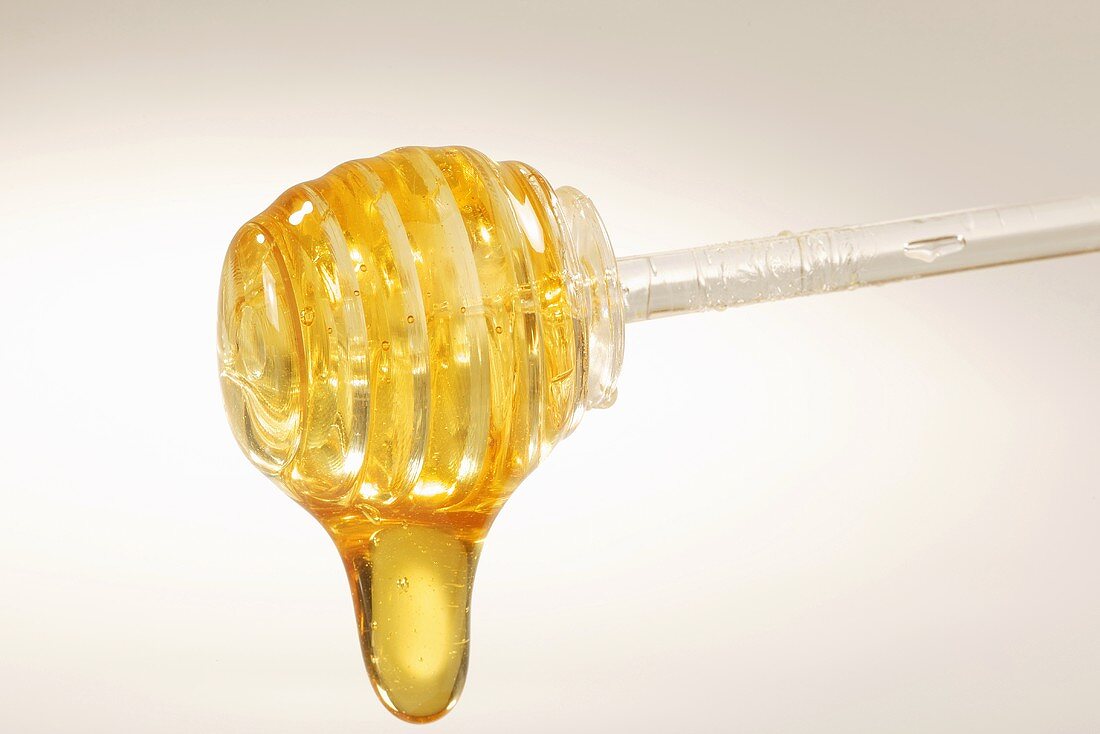 Honey dripping off an acrylic spoon