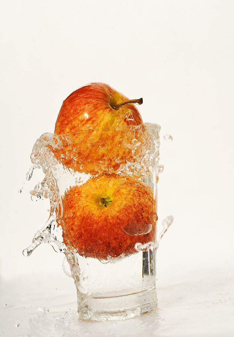 Two Gala apples in a glass of water