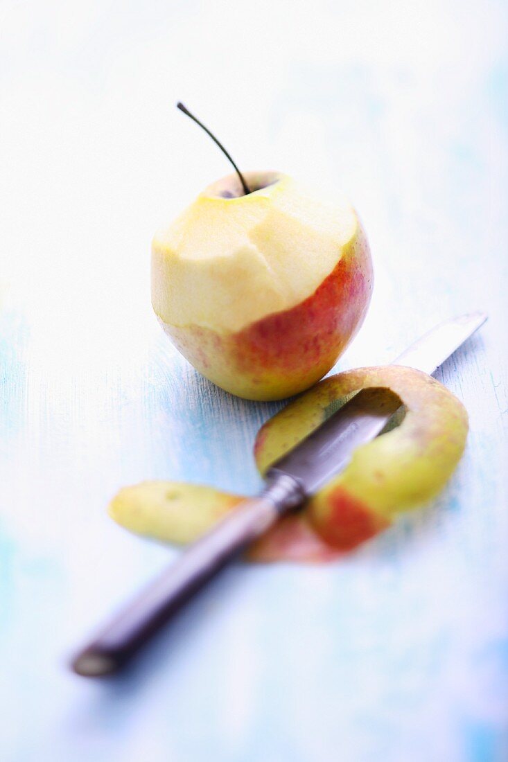 A half-peeled apple with a knife