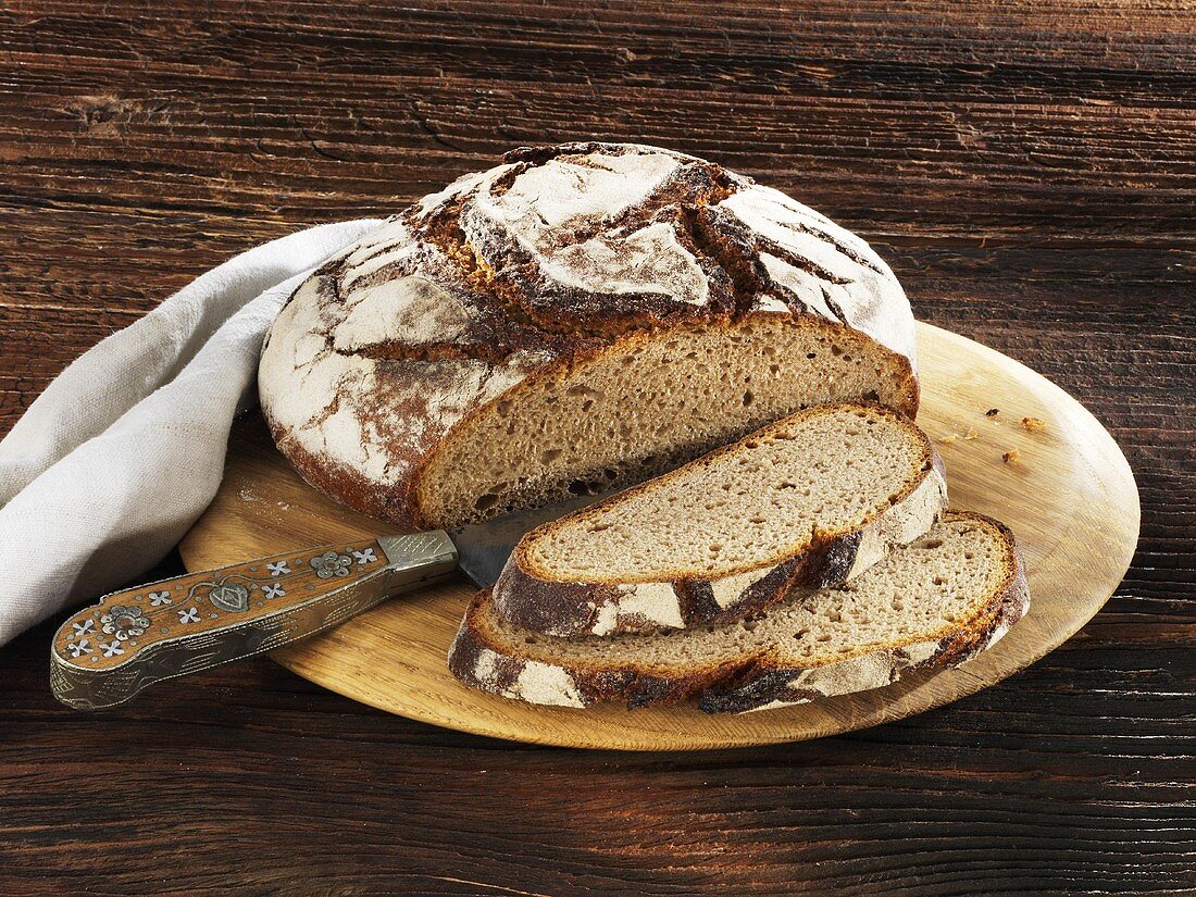 Rustikales Landbrot, angeschnitten, auf Holzteller