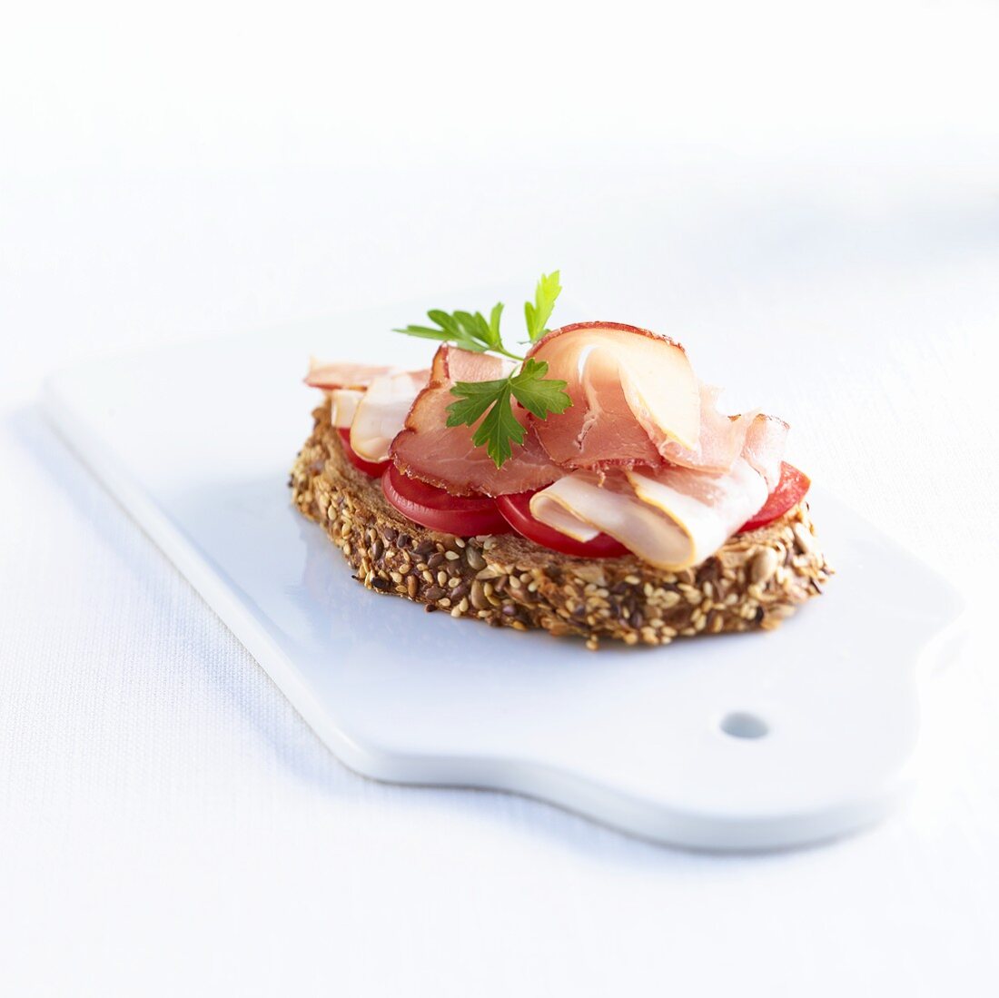 A slice of wholemeal bread with tomatoes and ham