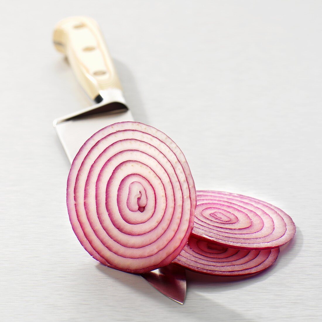 Slices of red onion on a knife