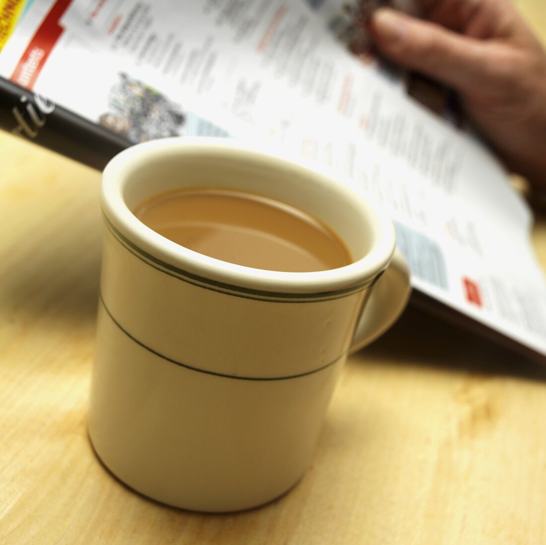 Tasse Kaffee, Hand hält Zeitung