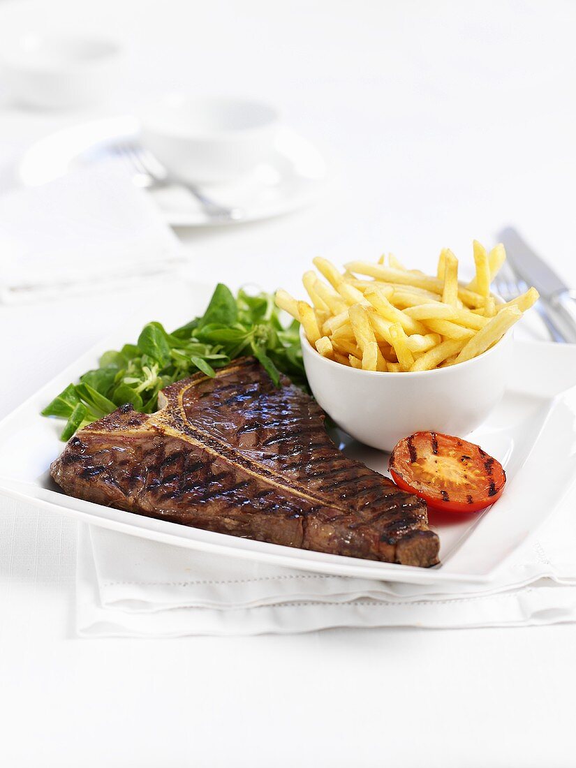 T-bone steak with chips and grilled tomatoes