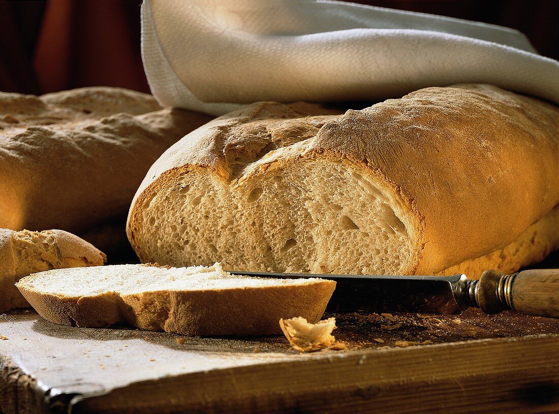 Italian Bread Loaf with a Slice on a Cutting Board