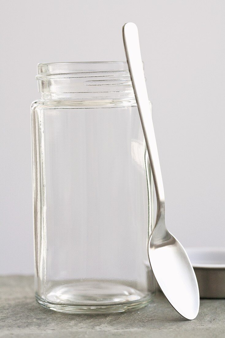 A spoon leaning against a screw-top jar