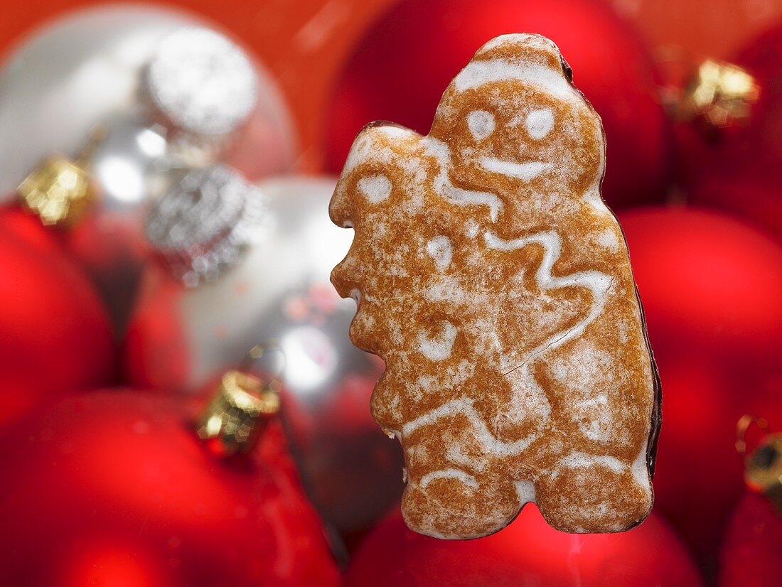 A Christmas biscuit with Christmas tree baubles in the background