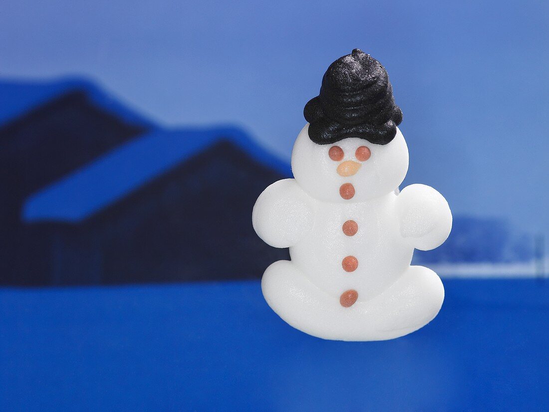 A sugar snowman in front of a winter landscape