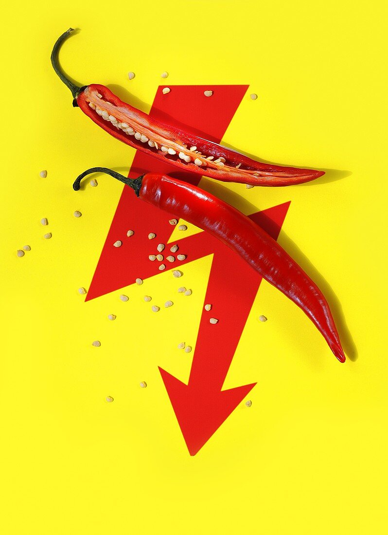 A sliced-open chilli pepper on a red arrow