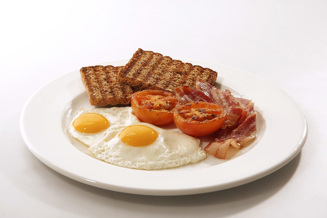 Englisches Frühstück (Spiegelei, Bacon, Vollkorntoast, Tomaten)