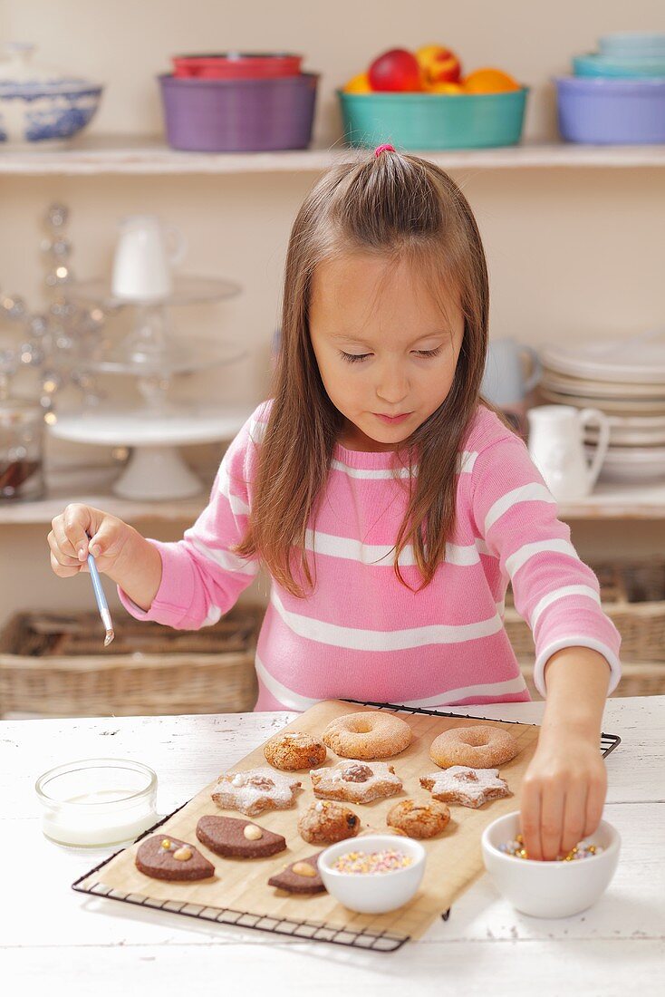 A girl decorating biscuits with sugar pearls