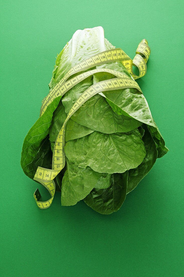 A cos lettuce and a measuring tape on a green surface