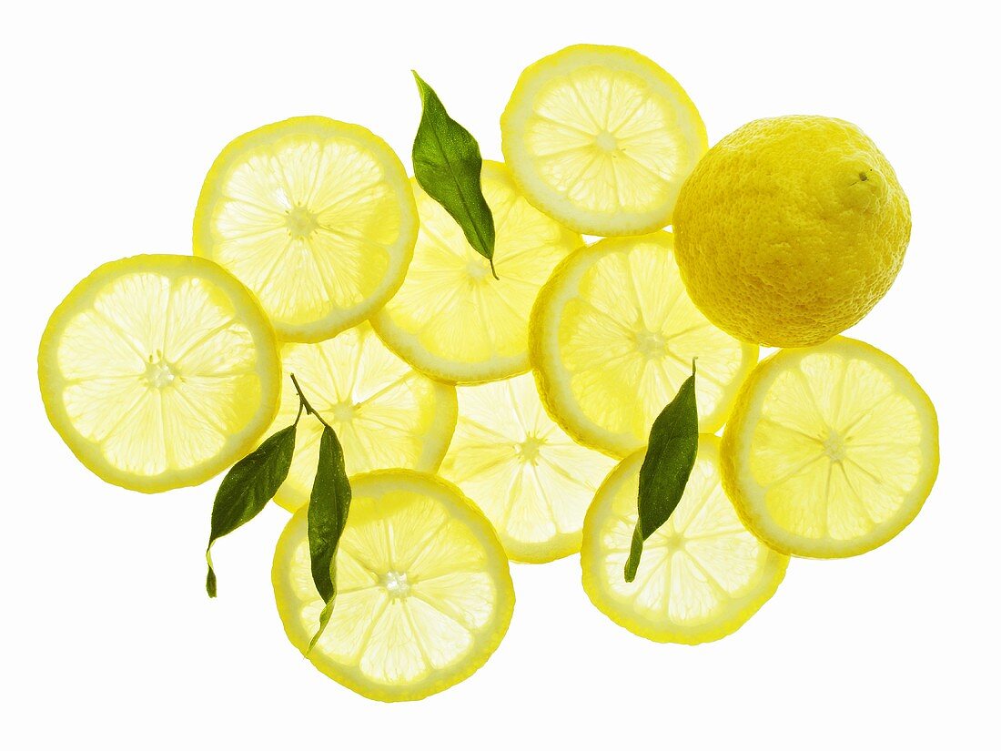 A whole lemon, lemon slices and leaves