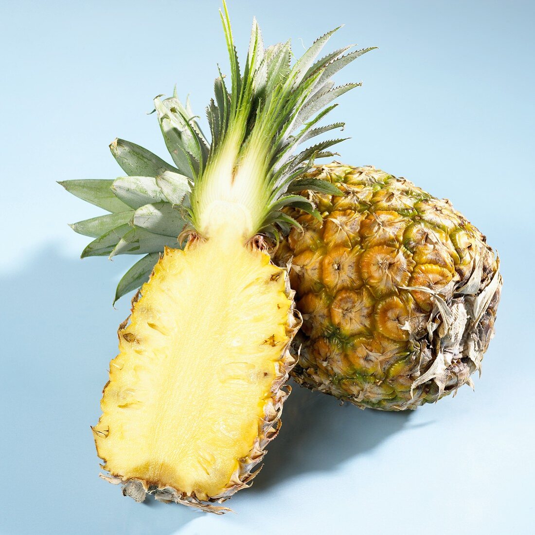 Half a pineapple in front of a whole pineapple