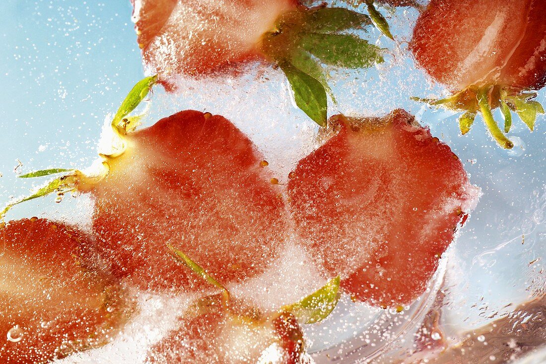 Gefrorene Erdbeerhälften in einem Eisblock