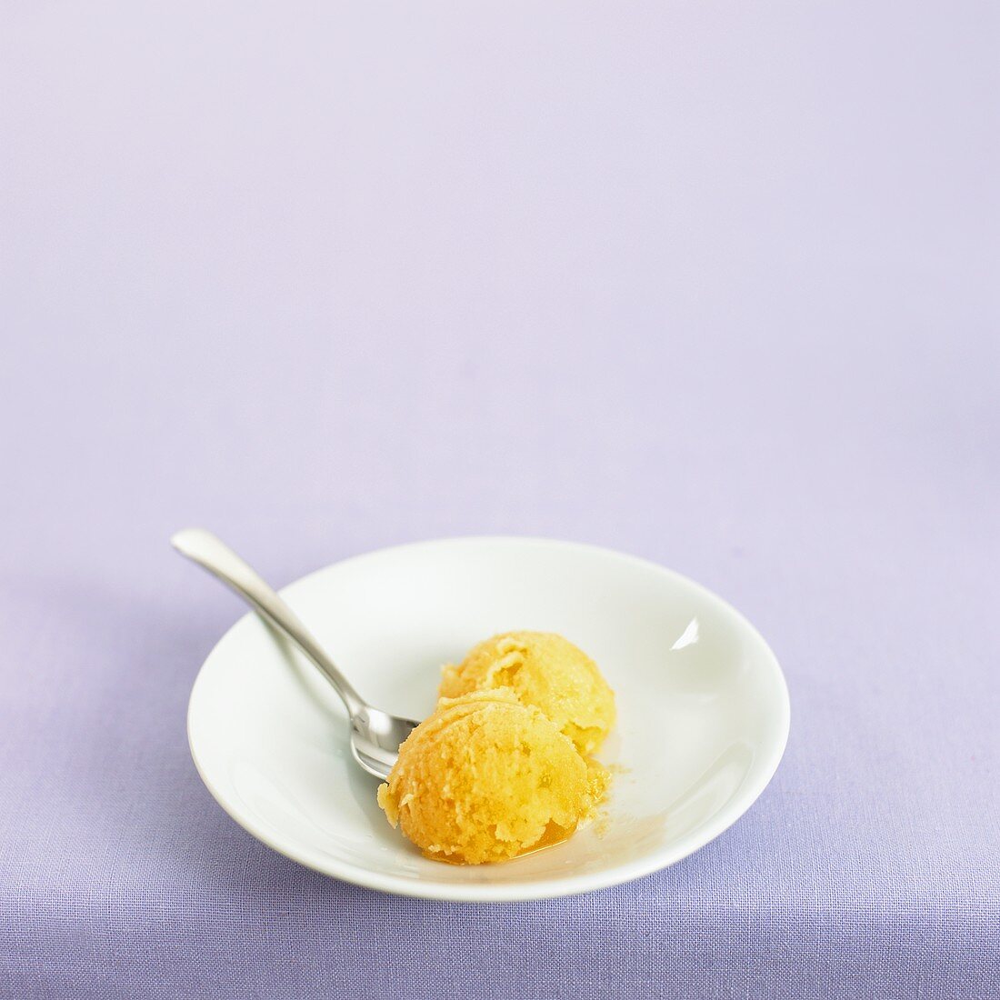Two scoops of orange sorbet on a plate