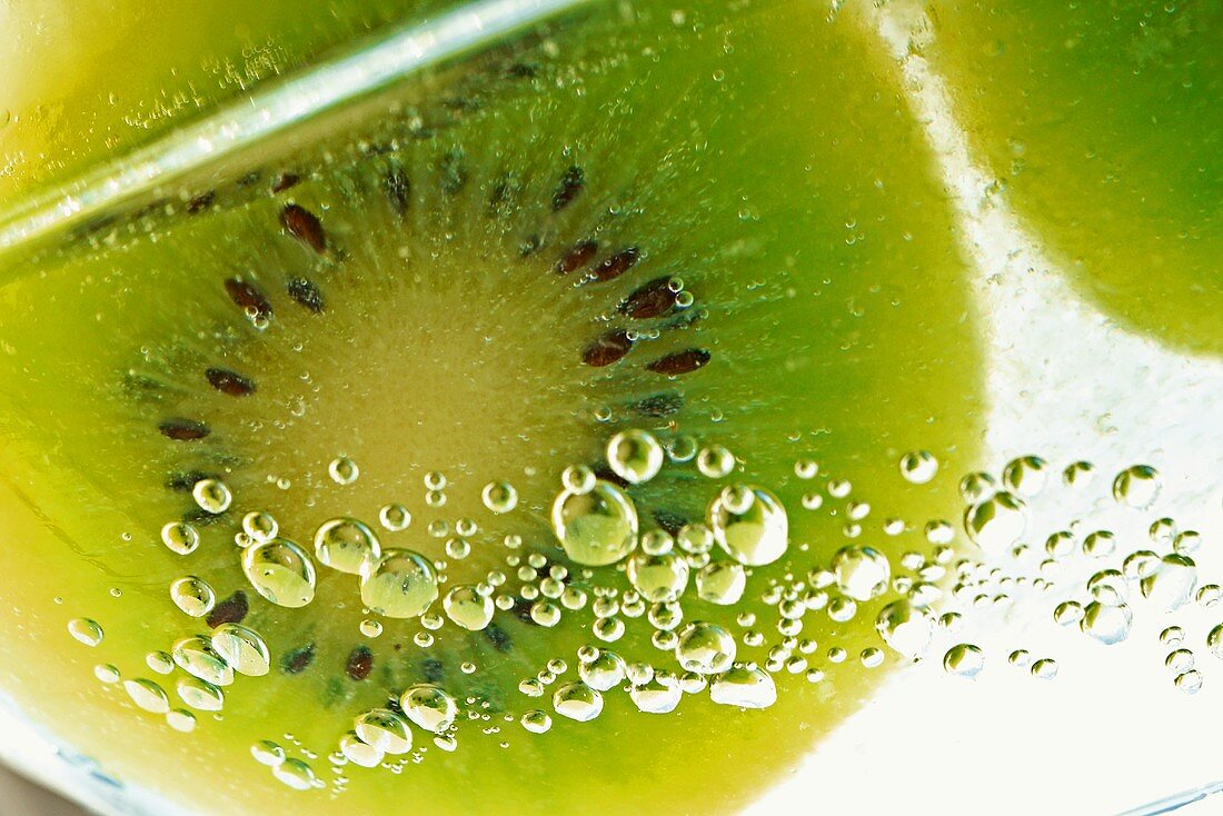 Slice of kiwi fruit and air bubbles in a glass