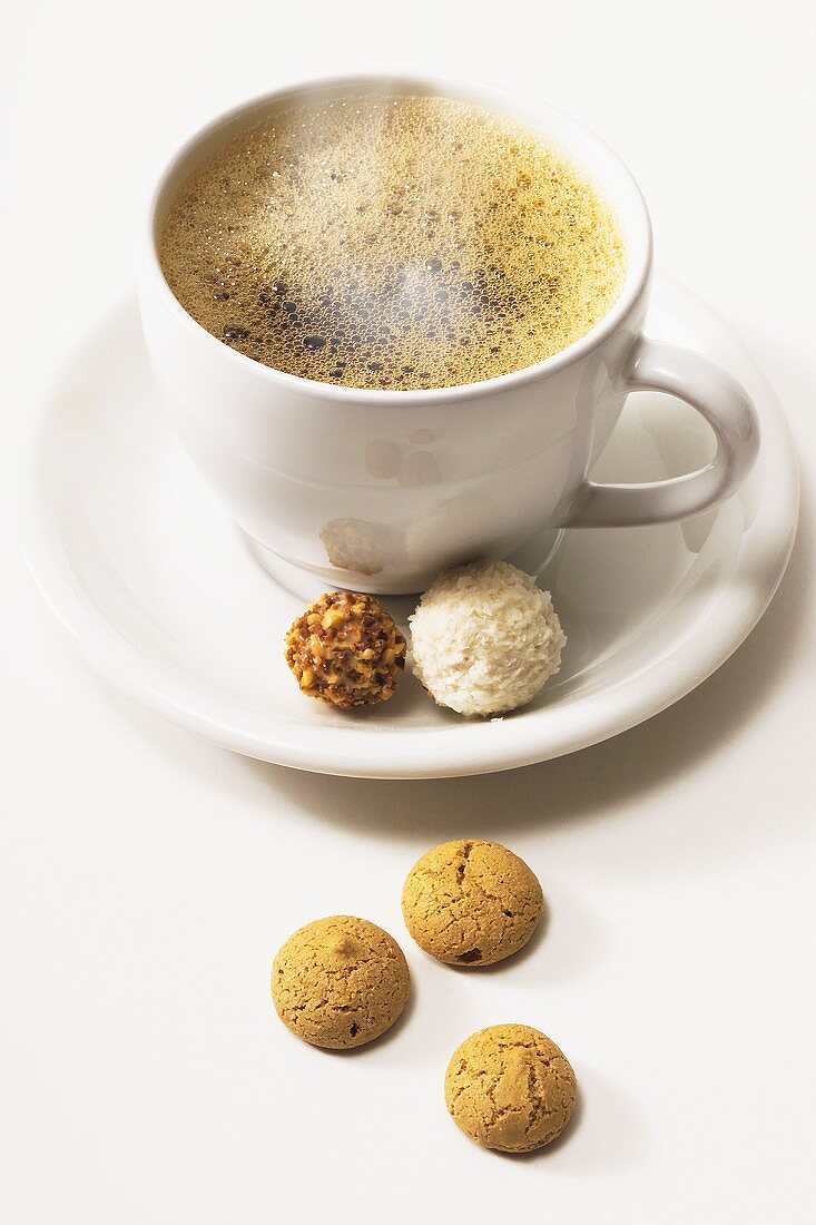 Steaming coffee cup with two chocolates and amarettini