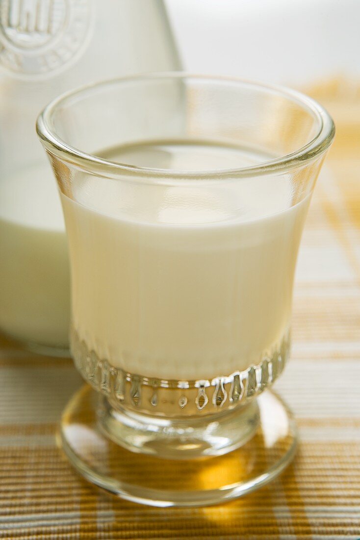 Glass of milk in front of carafe of milk