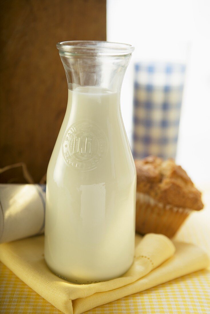 Carafe of milk and muffin on a fabric napkin