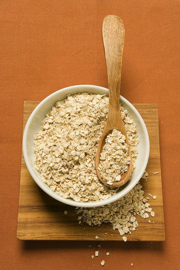 Rolled oats in a bowl with wooden spoon
