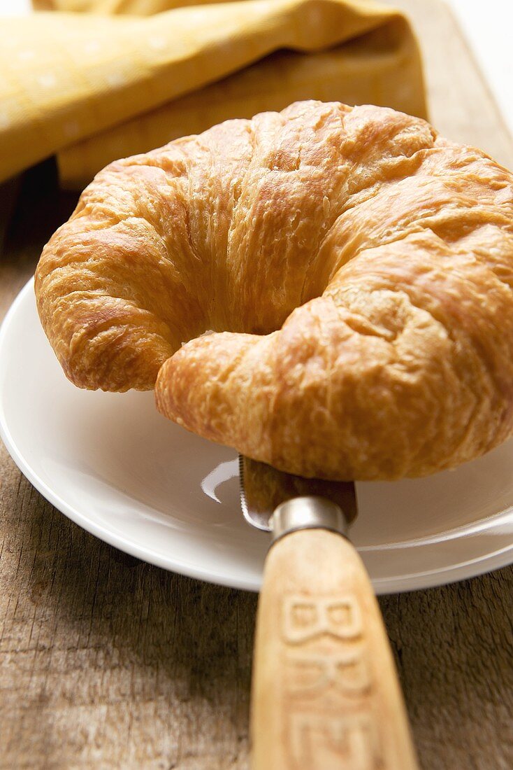 Croissant mit Messer auf Teller