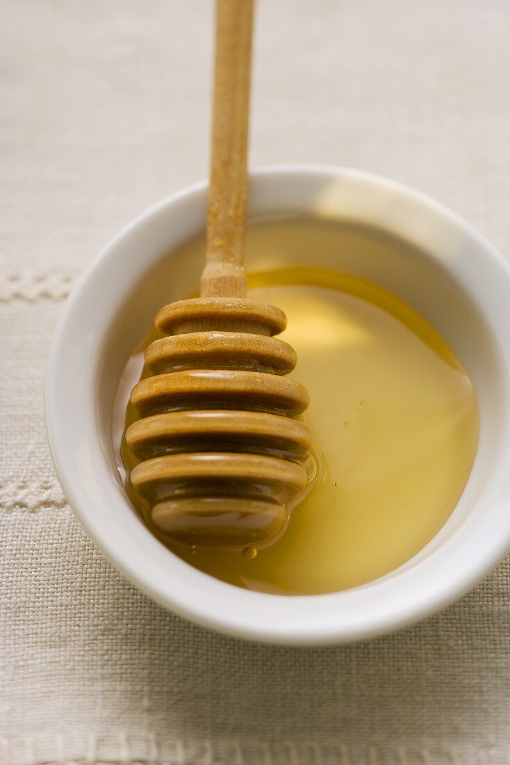 Honey dipper in a small bowl of honey