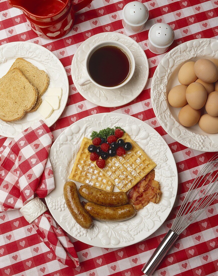 Frühstück mit Waffeln, Würstchen, Bacon, Toast, Kaffee, Eiern