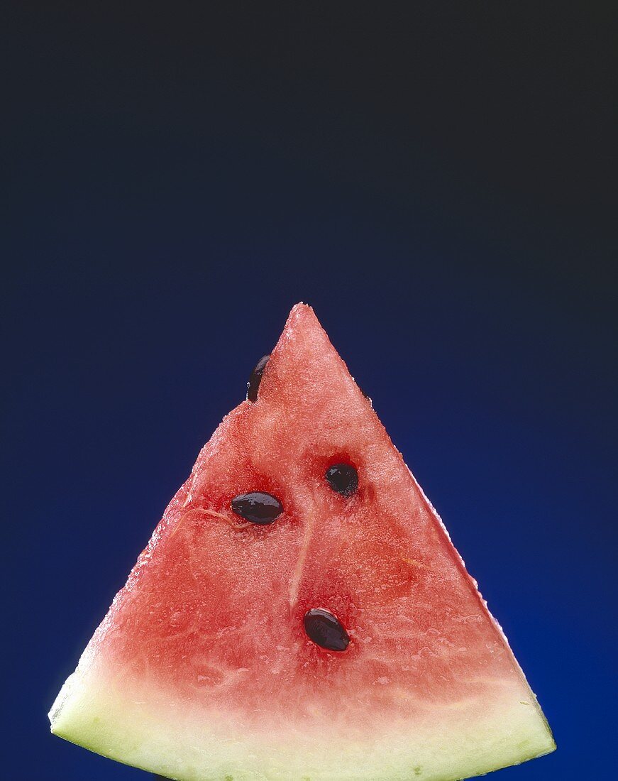 Slice of Watermelon with Seeds on a Blue Background