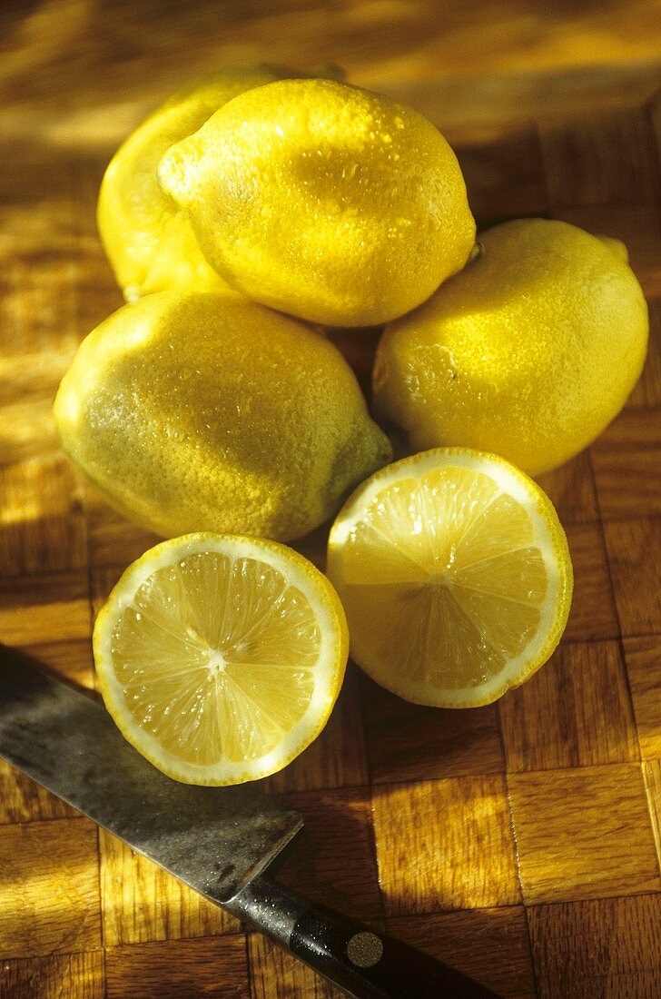 Whole Fresh Lemons with a Halved Lemon; Knife