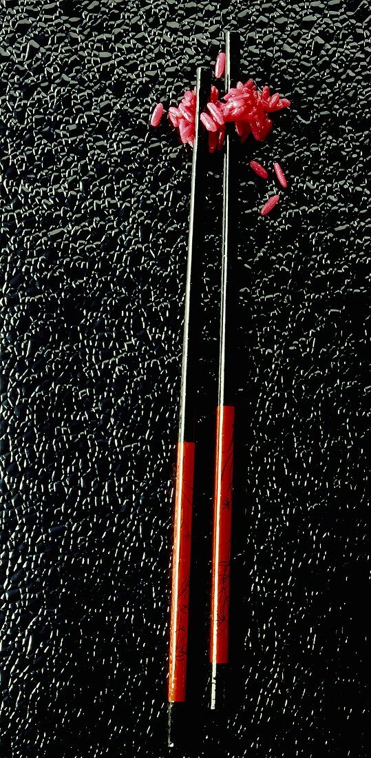 Red rice with chopsticks on black background