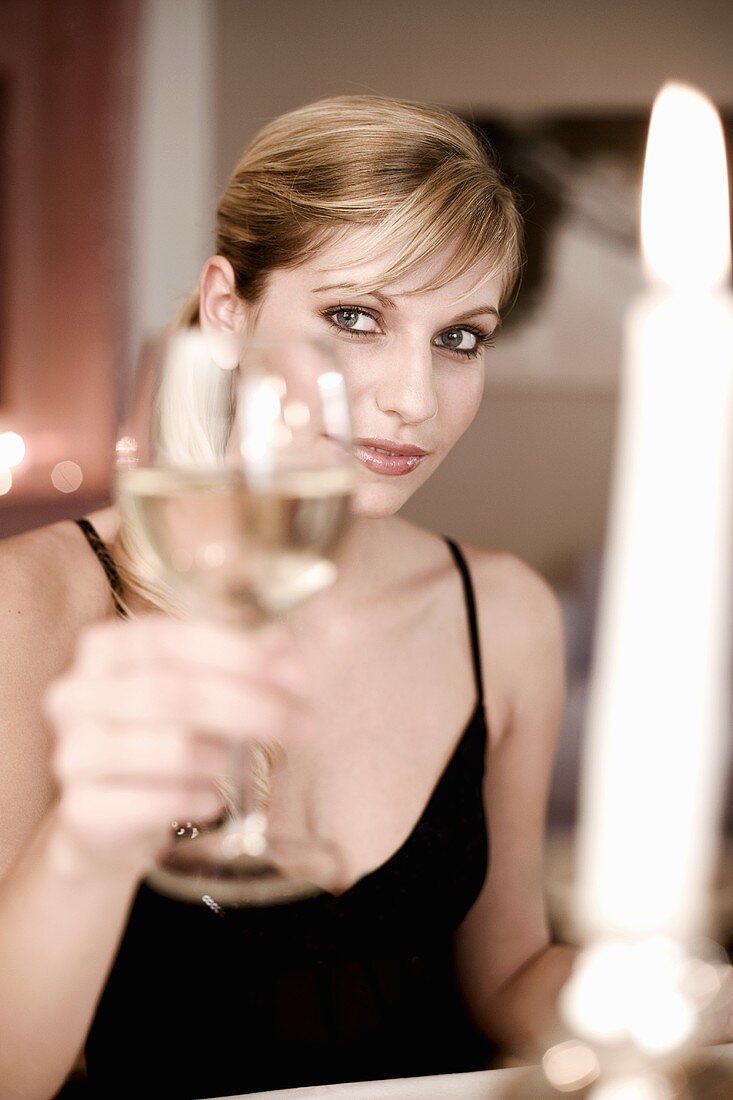 Junge Frau hält Weinglas zum anstossen