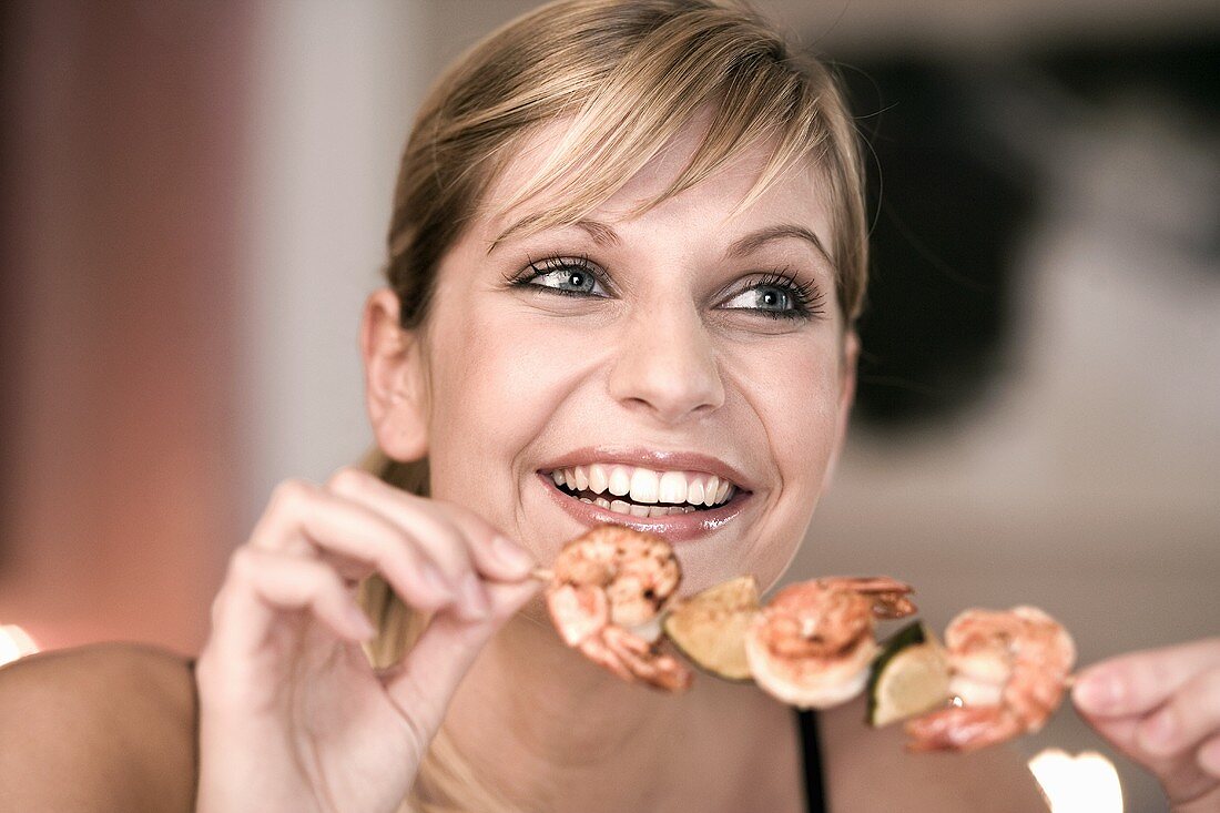 Young woman with shrimp kebab in her hand