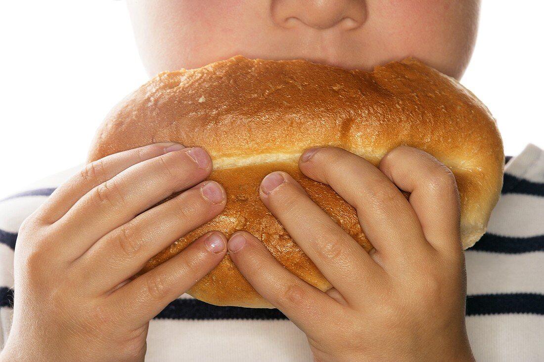 Small child biting into a bread roll