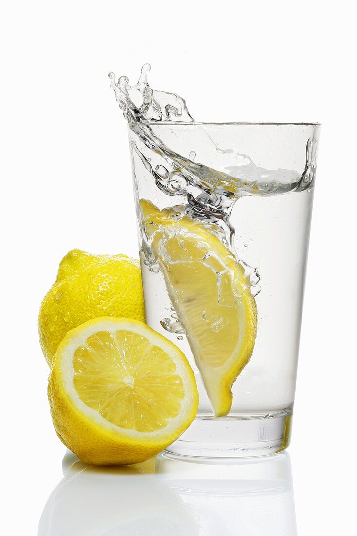 A wedge of lemon falling into a glass of water