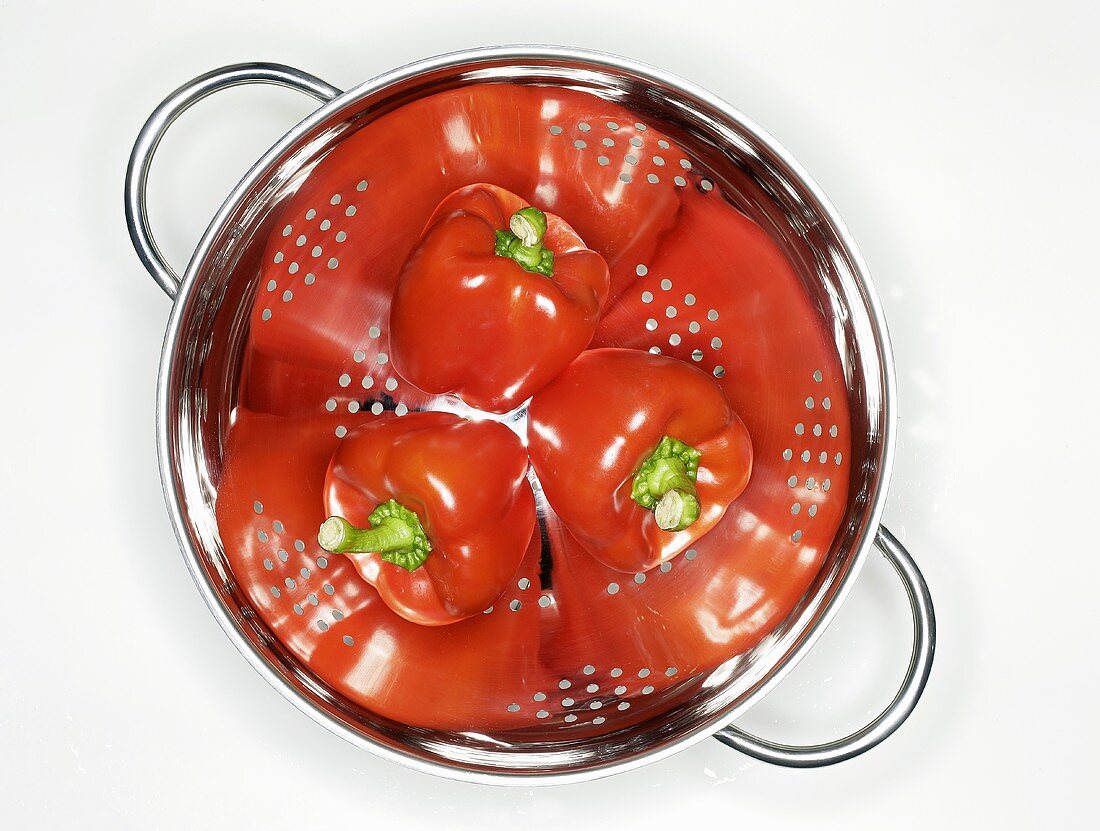 Three red peppers in a colander