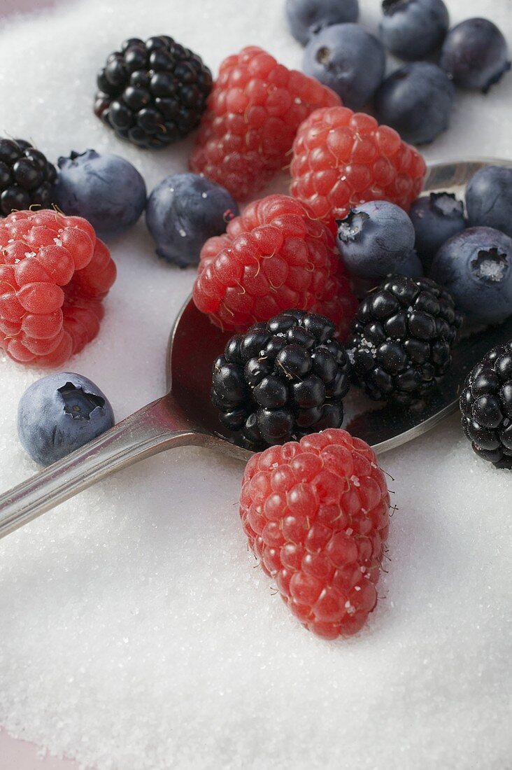 A spoon and mixed berries in sugar
