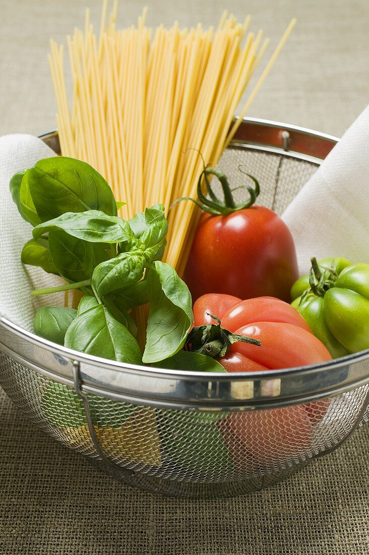 Tomaten, Spaghetti und Basilikum in einem Sieb