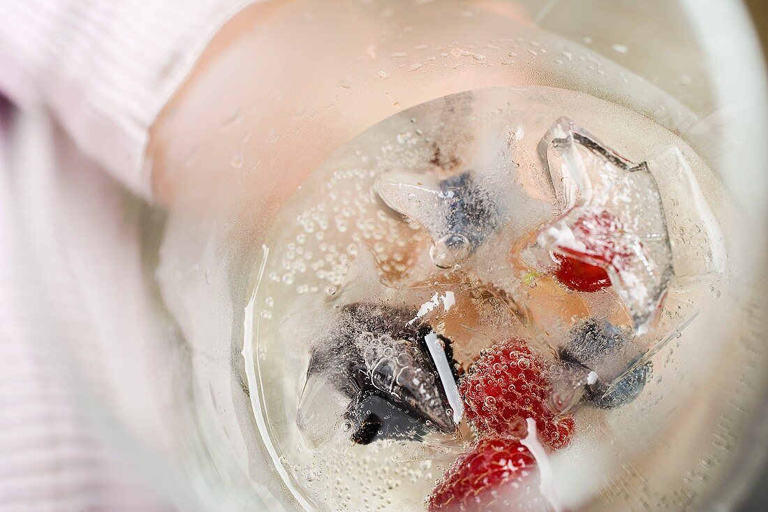 A glass of champagne with berry ice cubes